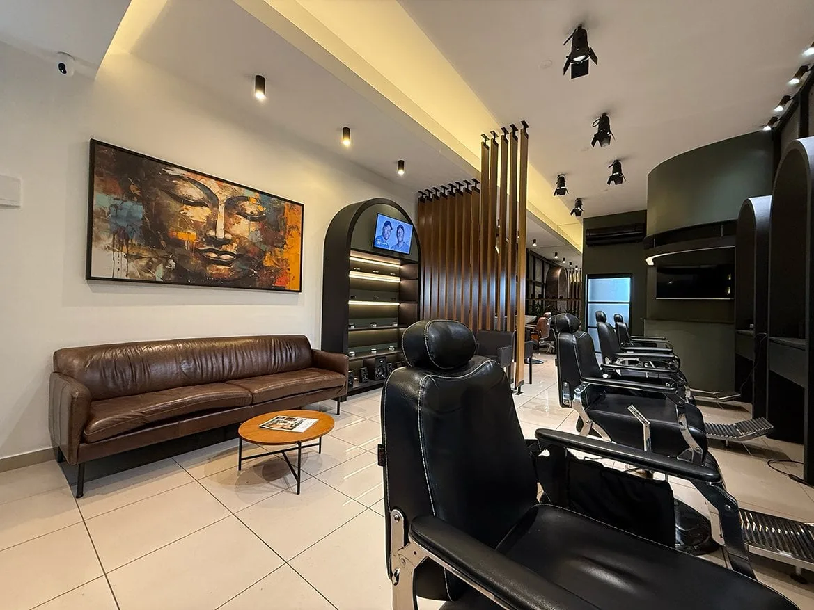 Interior da Kóden Barbearia, sofá de couro, cadeiras e estações de corte